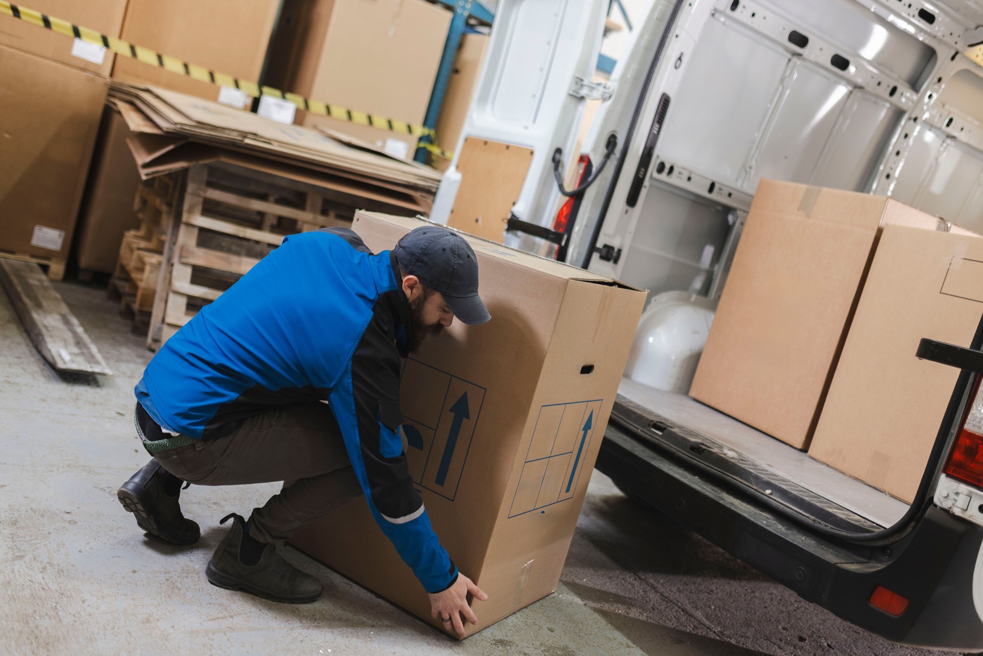 Deliverer prepares the packages for delivery, puts the cardboard boxes in the trunk of the delivery van